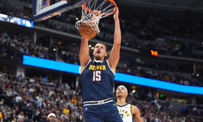 Denver Nuggets center Nikola Jokić, fronbt, dunks the ball for a basket over Indiana Pacers guard/forward Andrew Nembhard in the first half of an NBA basketball game Saturday, Nov. 8, 2025, in Denver. (AP Photo/David Zalubowski)
