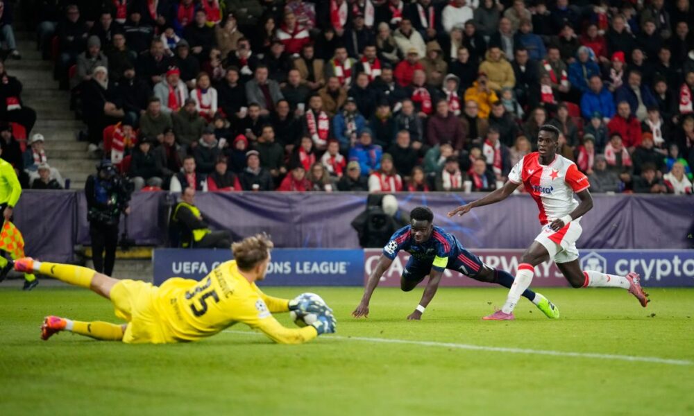 Slavia's goalkeeper Jakub Markovic, left, makes a save in front of Arsenal's Bukayo Saka, center, as Slavia's Youssoupha Mbodjiduring looks on the Champions League opening phase soccer match between Slavia Prague and Arsenal in Prague, Czech Republic, Tuesday, Nov. 4, 2025. (AP Photo/Petr David Josek)