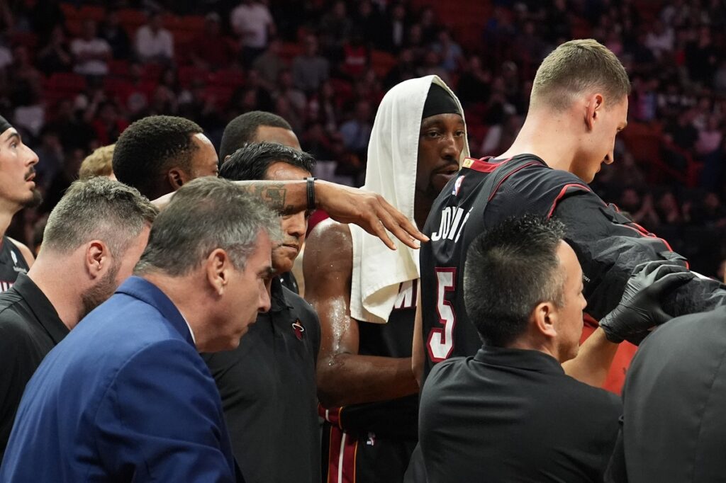 Miami Heat forward Nikola Jovic, top, right, is. helped off the court during the first half of an NBA basketball game against the Toronto Raptors, Monday, Dec. 15, 2025, in Miami. (AP Photo/Lynne Sladky)