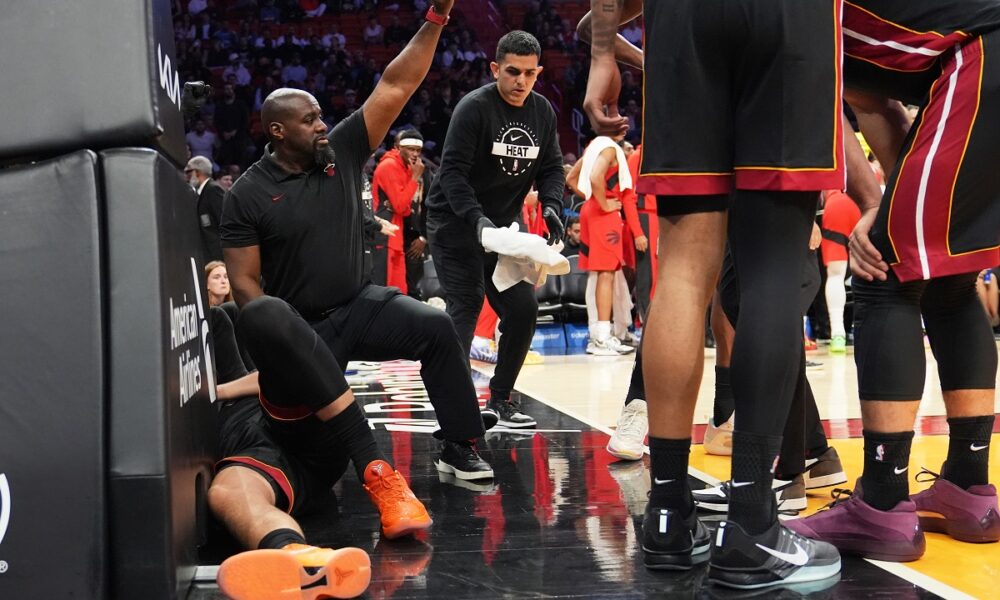 A Member of the Miami Heat coaching staff gestures as forward Nikola Jovic, left, lies on the court during the first half of an NBA basketball game against the Toronto Raptors, Monday, Dec. 15, 2025, in Miami. (AP Photo/Lynne Sladky)