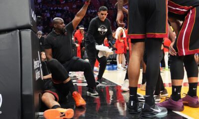 A Member of the Miami Heat coaching staff gestures as forward Nikola Jovic, left, lies on the court during the first half of an NBA basketball game against the Toronto Raptors, Monday, Dec. 15, 2025, in Miami. (AP Photo/Lynne Sladky)