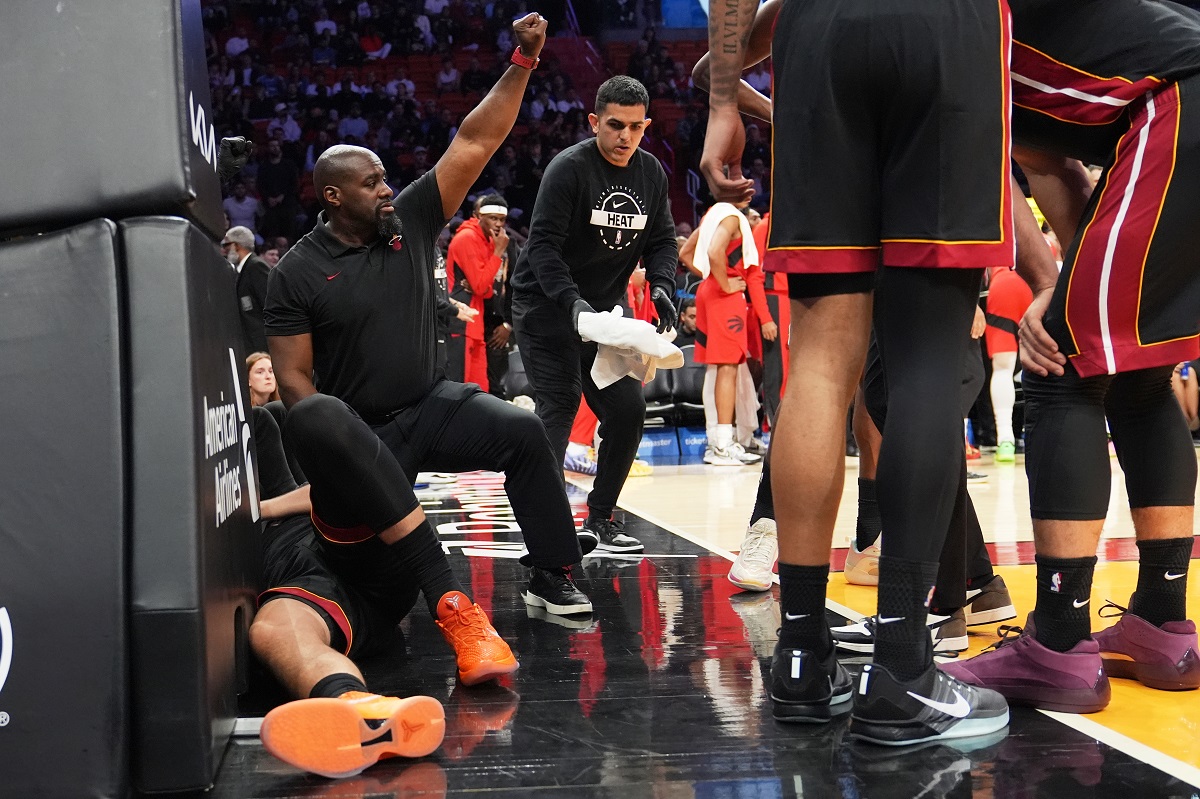 A Member of the Miami Heat coaching staff gestures as forward Nikola Jovic, left, lies on the court during the first half of an NBA basketball game against the Toronto Raptors, Monday, Dec. 15, 2025, in Miami. (AP Photo/Lynne Sladky)