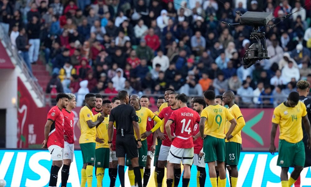 Players gather around the referee Pacifique Ndabihawenimana while a penalty kick check is being conducted during the Africa Cup of Nations group B soccer match between Egypt and South Africa in Agadir, Morocco, Friday, Dec. 26, 2025. (AP Photo/Themba Hadebe)
