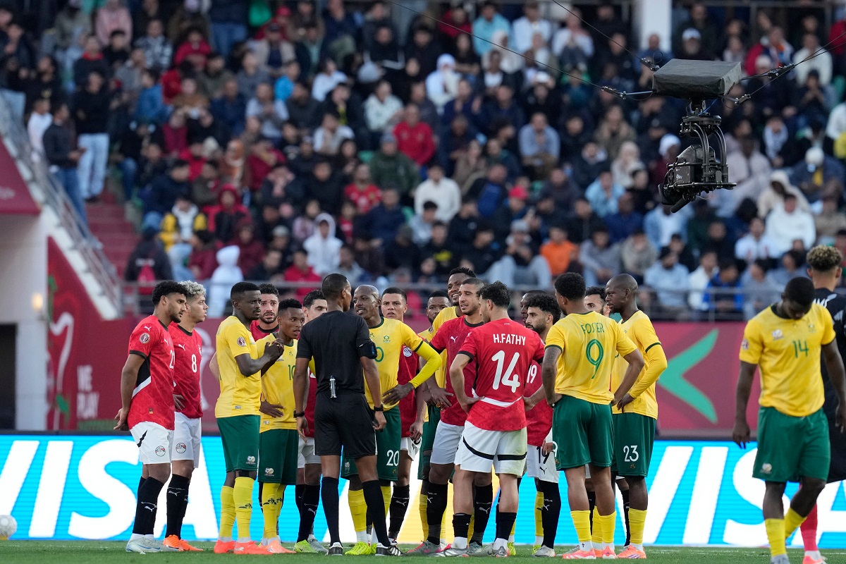 Players gather around the referee Pacifique Ndabihawenimana while a penalty kick check is being conducted during the Africa Cup of Nations group B soccer match between Egypt and South Africa in Agadir, Morocco, Friday, Dec. 26, 2025. (AP Photo/Themba Hadebe)