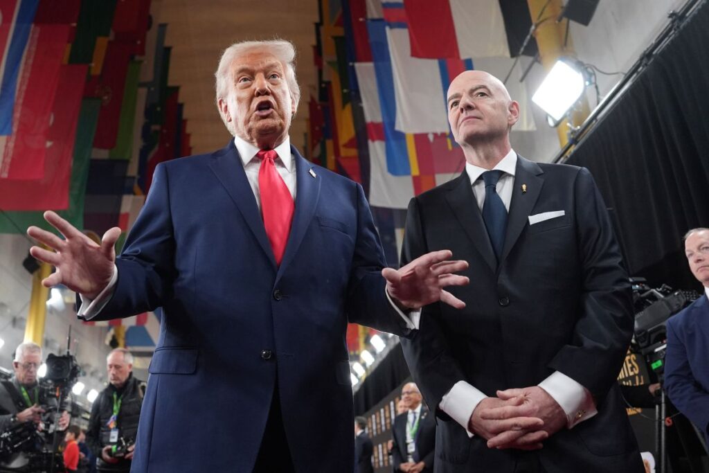 President Donald Trump, center, speaking to members of the media during his arrival with FIFA President Gianni Infantino, right, at the Kennedy Center for the 2026 FIFA World Cup draw, Friday, Dec. 5, 2025, in Washington. (AP Photo/Evan Vucci)