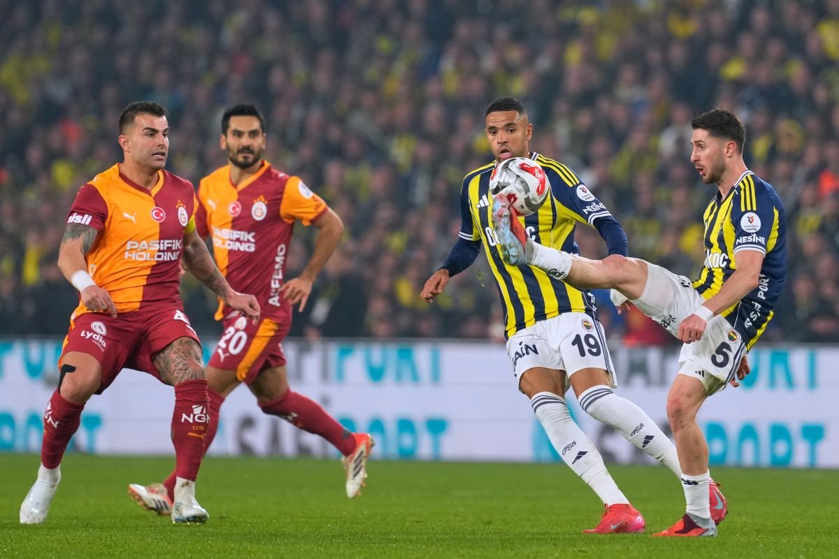 Fenerbahce's Ismail Yuksek, right, plays the ball next to Galatasaray's defenders during a Turkish Super Lig soccer match between Fenerbahce and Galatasaray, in Istanbul, Turkey, Monday, Dec. 1, 2025. (AP Photo/Khalil Hamra)