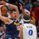 Denver Nuggets center Nikola Jokić, left, pulls in a rebound as Orlando Magic center Wendell Carter Jr., back right, and guard Anthony Black (0) defend in the second half of an NBA basketball game Thursday, Dec. 18, 2025, in Denver. (AP Photo/David Zalubowski)