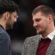 Injured Washington Wizards forward Tristan Vukcevic, left, chats with injured Denver Nuggets center Nikola Jokić before the start of the second half of an NBA basketball game Saturday, Jan. 17, 2026, in Denver. (AP Photo/David Zalubowski)
