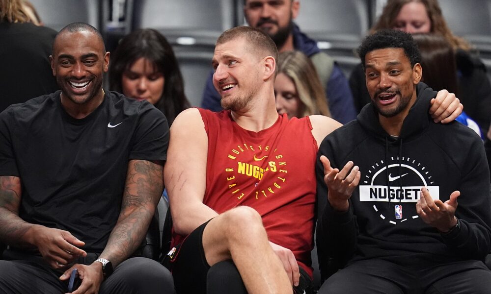 Returning from an injury, Denver Nuggets center Nikola Jokić, center, jokes with player development coaches Darrell Arthur, left, and Cam Griffin, right, before warming up for an NBA basketball game against the Los Angeles Clippers, Friday, Jan. 30, 2026, in Denver. (AP Photo/David Zalubowski)