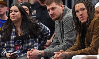 Injured Denver Nuggets center Nikola Jokić, center, and forward Aaron Gordon look on from the bench in the second half of an NBA basketball game against the Charlotte Hornets Sunday, Jan. 18, 2026, in Denver. (AP Photo/David Zalubowski)