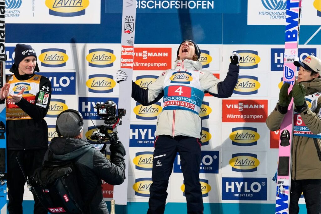 Daniel Tschofenig, of Austria, center, celebrates on the podium flanked by second placed Domen Prevc, of Slovenia, left, and third placed Ryoyu Kobayashi, of Japan, after winning the fourth stage of the Four Hills ski jumping tournament in Bischofshofen, Austria, Tuesday, Jan. 6, 2026. (AP Photo/Matthias Schrader)