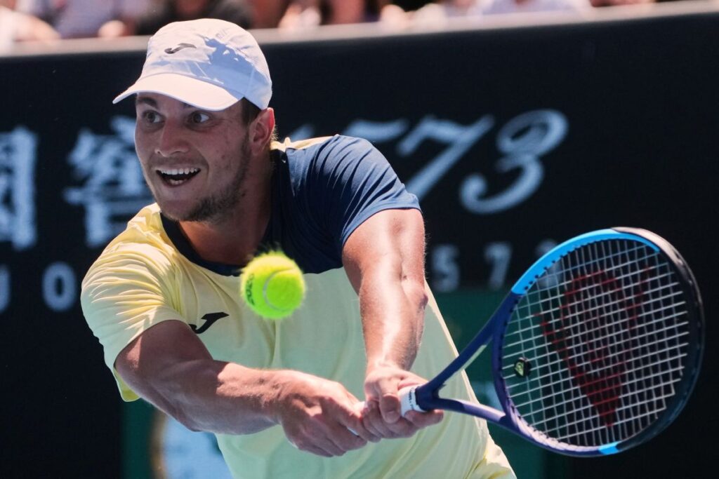 Miomir Kecmanovic of Serbia plays a backhand return to Tomas Martin Etcheverry of Argentina during their first round match at the Australian Open tennis championship in Melbourne, Australia, Sunday, Jan. 18, 2026. (AP Photo/Asanka Brendon Ratnayake)