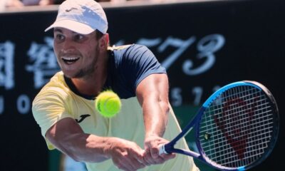 Miomir Kecmanovic of Serbia plays a backhand return to Tomas Martin Etcheverry of Argentina during their first round match at the Australian Open tennis championship in Melbourne, Australia, Sunday, Jan. 18, 2026. (AP Photo/Asanka Brendon Ratnayake)