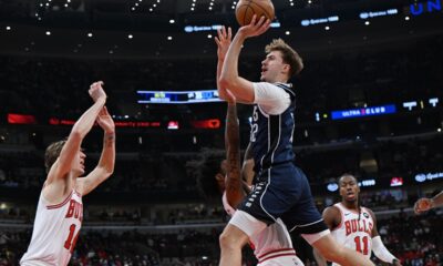 Dallas Mavericks' Cooper Flagg goes up for a shot against Chicago Bulls' Coby White and Matas Buzelis (14) during the first half of an NBA basketball game, Saturday, Jan. 10, 2026, in Chicago. (AP Photo/Paul Beaty)