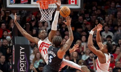 Toronto Raptors center Mo Bamba (11) and forward Scottie Barnes, right, defend against Orlando Magic forward Paolo Banchero (5) as he shoots during first half NBA action in Toronto on Monday Dec. 29, 2025. THE (Frank Gunn/The Canadian Press via AP)
