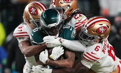 Philadelphia Eagles wide receiver DeVonta Smith (6) is stopped by San Francisco 49ers cornerback Deommodore Lenoir (2), 49ers safety Ji'ayir Brown (27) and 49ers safety Malik Mustapha (6) during the first half of an NFL wild-card playoff football game Sunday, Jan. 11, 2026, in Philadelphia. (AP Photo/Matt Rourke)