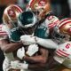 Philadelphia Eagles wide receiver DeVonta Smith (6) is stopped by San Francisco 49ers cornerback Deommodore Lenoir (2), 49ers safety Ji'ayir Brown (27) and 49ers safety Malik Mustapha (6) during the first half of an NFL wild-card playoff football game Sunday, Jan. 11, 2026, in Philadelphia. (AP Photo/Matt Rourke)