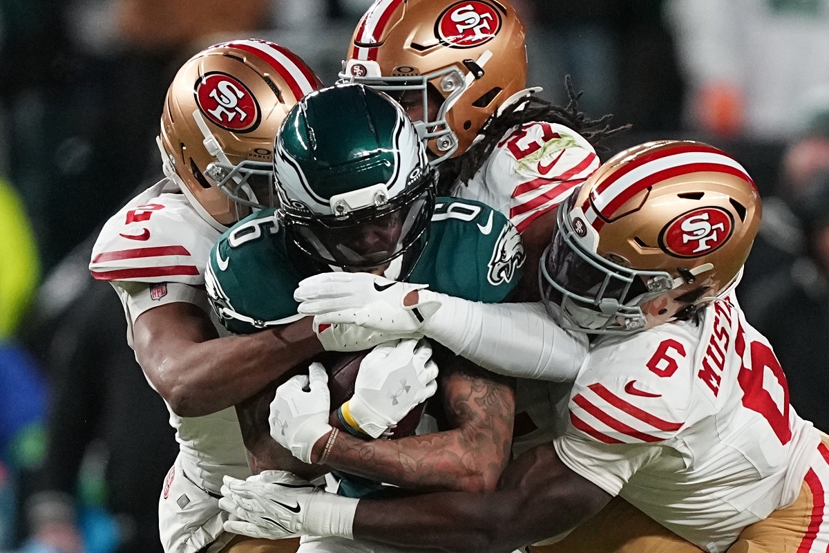 Philadelphia Eagles wide receiver DeVonta Smith (6) is stopped by San Francisco 49ers cornerback Deommodore Lenoir (2), 49ers safety Ji'ayir Brown (27) and 49ers safety Malik Mustapha (6) during the first half of an NFL wild-card playoff football game Sunday, Jan. 11, 2026, in Philadelphia. (AP Photo/Matt Rourke)