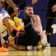 Golden State Warriors guard Brandin Podziemski, center, falls in the lap of Denver Nuggets center Nikola Jokic, center right, before a jump ball is called during the first half of an NBA basketball game, Sunday, Feb. 22, 2026, in San Francisco. (AP Photo/Kelley L Cox)