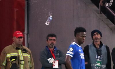 A plastic bottle filled with water is thrown from the stands toward Real Madrid's Vinícius Júnior during a Champions League playoff soccer match between Benfica and Real Madrid in Lisbon, Portugal, Tuesday, Feb. 17, 2026. (AP Photo/Pedro Rocha)
