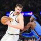 Denver Nuggets center Nikola Jokić, left, drives against Oklahoma City Thunder guard Luguentz Dort (5) during the first half of an NBA basketball game, Monday, Mar. 9, 2026, in Oklahoma City. (AP Photo/Gerald Leong)