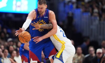 Denver Nuggets center Nikola Jokić, left, struggles to field a pass as Golden State Warriors forward Draymond Green defends in the second half of an NBA basketball game Sunday, March 29, 2026, in Denver. (AP Photo/David Zalubowski)