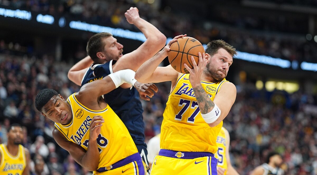 Los Angeles Lakers guard Luka Dončić, right, pulls in a rebound as forward Rui Hachimura, left, boxes out Denver Nuggets center Nikola Jokić in the second half of an NBA basketball game Thursday, March 5, 2026, in Denver. (AP Photo/David Zalubowski)