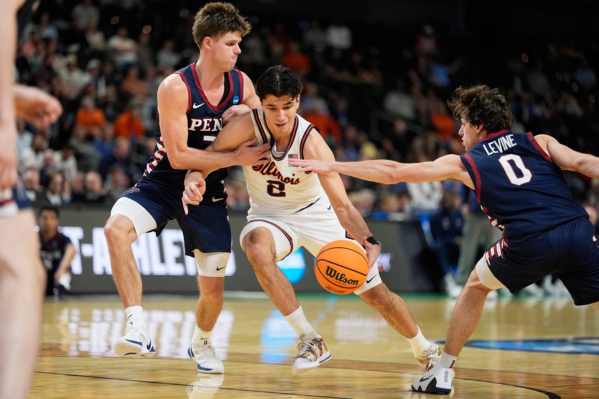 Illinois guard Andrej Stojakovic drives to the basket between Pennsylvania forward Michael Zanoni and guard AJ Levine during the second half in the first round of the NCAA college basketball tournament, Thursday, March 19, 2026, in Greenville, S.C. (AP Photo/Chris Carlson)