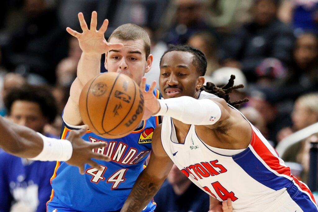 Oklahoma City Thunder guard Nikola Topic (44) and Detroit Pistons guard Daniss Jenkins scramble for a loose ball during the second half of an NBA basketball game, Wednesday, Feb. 25, 2026, in Detroit. (AP Photo/Duane Burleson)