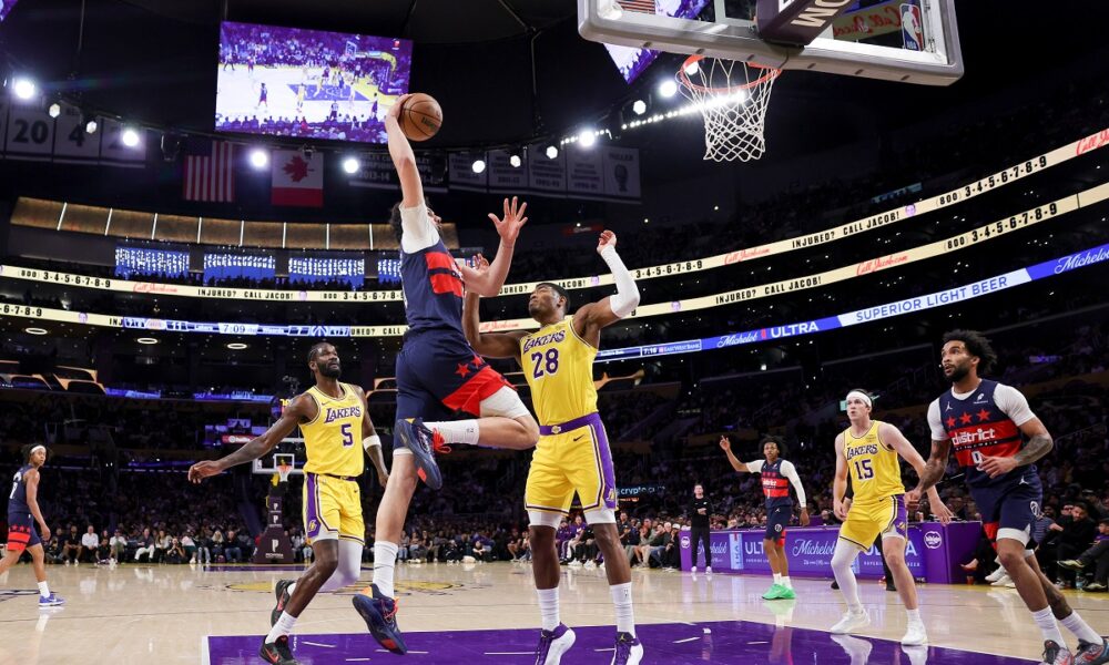 Washington Wizards forward Tristan Vukcevic, second from left, dunks against Los Angeles Lakers center Deandre Ayton, left, and Los Angeles Lakers forward Rui Hachimura, center, during the first half of an NBA basketball game Monday, March 30, 2026, in Los Angeles. (AP Photo/Ryan Sun)