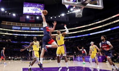Washington Wizards forward Tristan Vukcevic, second from left, dunks against Los Angeles Lakers center Deandre Ayton, left, and Los Angeles Lakers forward Rui Hachimura, center, during the first half of an NBA basketball game Monday, March 30, 2026, in Los Angeles. (AP Photo/Ryan Sun)