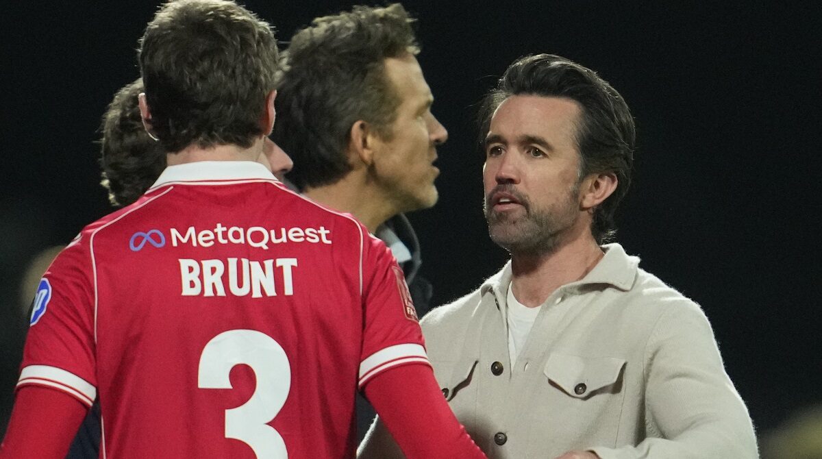 Actors and Wrexham owners Ryan Reynolds, center, and Rob McElhenney stand on the pitch after the fifth round FA Cup soccer match between Wrexham and Chelsea in Wrexham, Wales, Saturday, March 7, 2026. (AP Photo/Jon Super)