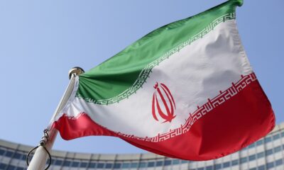 FILE - The Iranian national flag flies during a special session of an IAEA Board of Governors meeting in Vienna, Austria, March 2, 2026. (AP Photo/Heinz-Peter Bader, file)