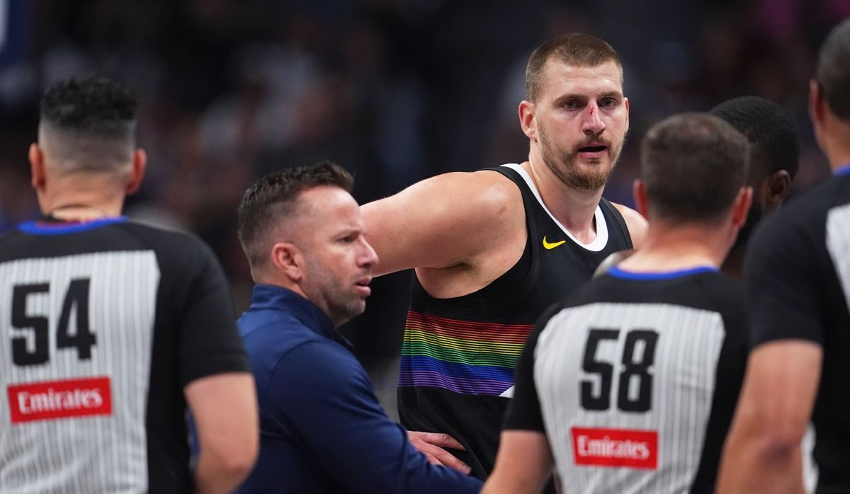 Denver Nuggets center Nikola Jokić, back right, argues for a call after being hit in the nose as assistant coach J.J. Barea, back left, intercedes with referees Ray Acosta, front left, and Josh Tiven in the first half of an NBA basketball game against the San Antonio Spurs, Saturday, April 4, 2026, in Denver. (AP Photo/David Zalubowski)