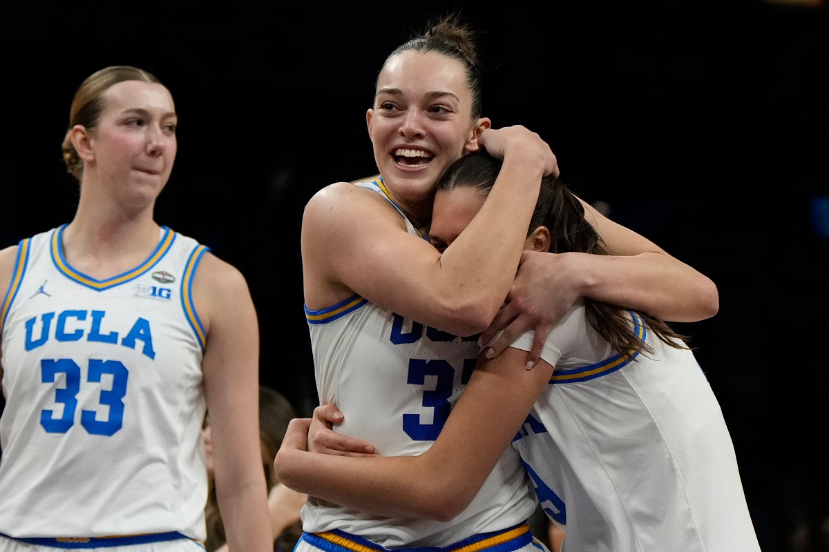 UCLA forward Angela Dugalic, second from left, embraces UCLA guard Lena Bilic (9) after defeating Texas in a women's NCAA college basketball tournament semifinal game at the Final Four, Friday, April 3, 2026, in Phoenix. (AP Photo/Ross D. Franklin)