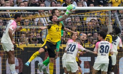 Leverkusen's goalkeeper Mark Flekken catches the ball as he challenges with Dortmund's Ramy Bensebaini during the German Bundesliga soccer match between Borussia Dortmund and Bayer Leverkusen in Dortmund, Germany, Saturday, April 11, 2026. (AP Photo/Martin Meissner)