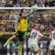 Leverkusen's goalkeeper Mark Flekken catches the ball as he challenges with Dortmund's Ramy Bensebaini during the German Bundesliga soccer match between Borussia Dortmund and Bayer Leverkusen in Dortmund, Germany, Saturday, April 11, 2026. (AP Photo/Martin Meissner)
