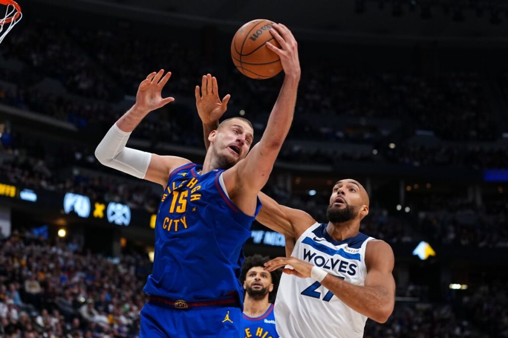 Denver Nuggets center Nikola Jokic (15) pulls down a rebound against Minnesota Timberwolves center Rudy Gobert (27) during the second half in Game 2 of a first-round NBA playoffs basketball series Monday, April 20, 2026, in Denver. (AP Photo/Jack Dempsey)