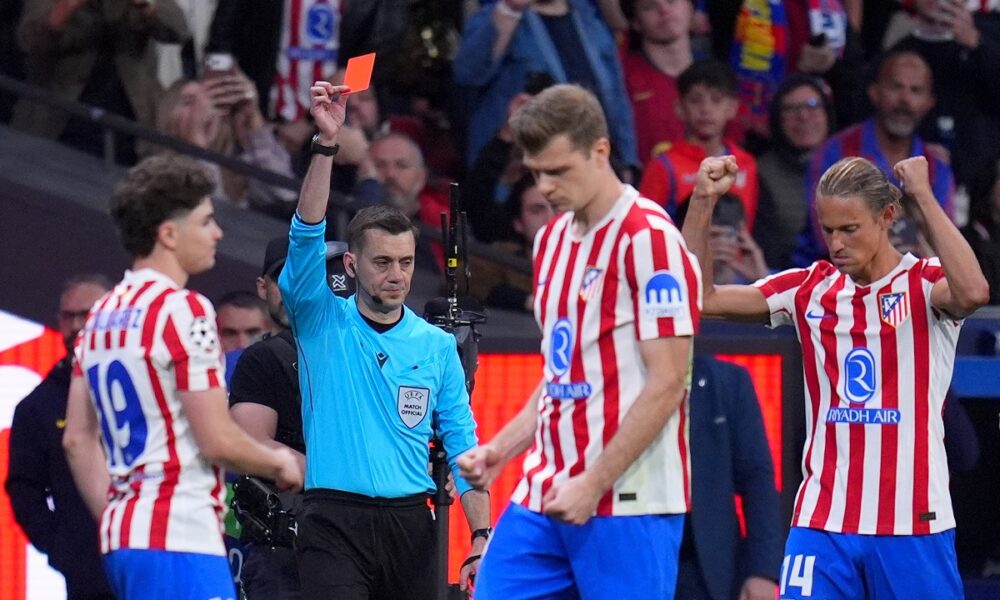 Referee Clement Turpin shows a red card to Barcelona's Eric Garcia during the Champions League quarterfinal second leg soccer match between Atletico Madrid and Barcelona in Madrid, Spain, Tuesday, April 14, 2026. (AP Photo/Manu Fernandez)