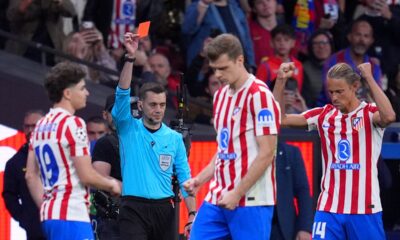 Referee Clement Turpin shows a red card to Barcelona's Eric Garcia during the Champions League quarterfinal second leg soccer match between Atletico Madrid and Barcelona in Madrid, Spain, Tuesday, April 14, 2026. (AP Photo/Manu Fernandez)