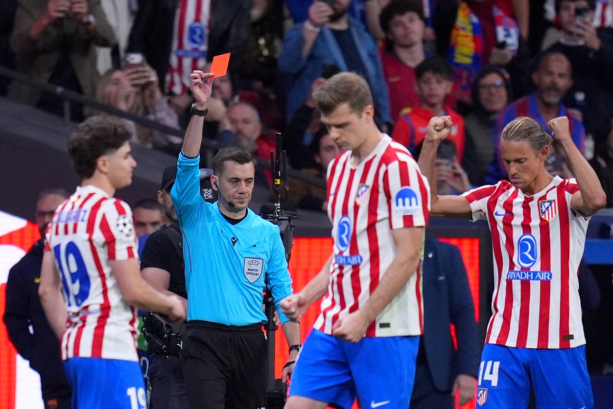 Referee Clement Turpin shows a red card to Barcelona's Eric Garcia during the Champions League quarterfinal second leg soccer match between Atletico Madrid and Barcelona in Madrid, Spain, Tuesday, April 14, 2026. (AP Photo/Manu Fernandez)