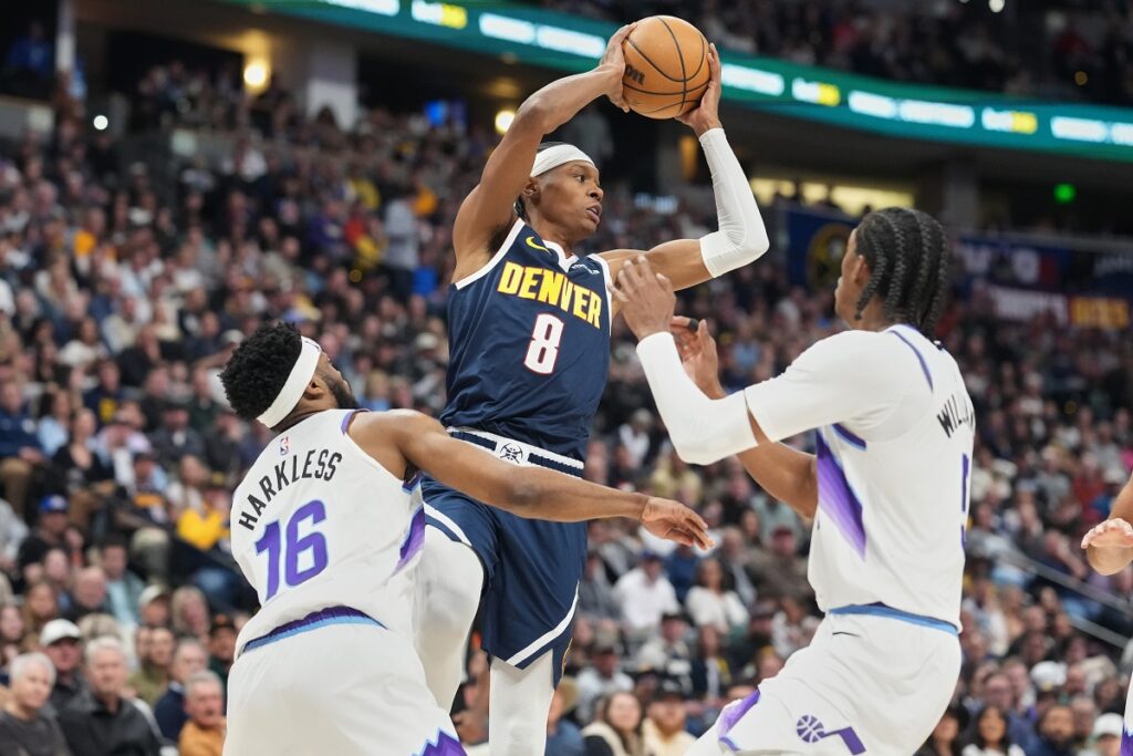 Denver Nuggets guard Peyton Watson, center, looks to pass the ball as Utah Jazz guard Elijah Harkless, left, and forward Cody Williams defend in the first half of an NBA basketball game Friday, March 27, 2026, in Denver. (AP Photo/David Zalubowski)