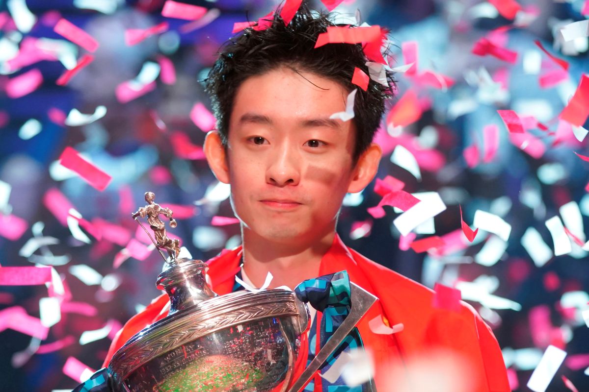China's poses for the media with the trophy and wearing the Chinese national flag, after winning the World Snooker Championship defeating England's Shaun Murphy in Sheffield, England, Monday, May 4, 2026.(AP Photo/Ian Hodgson)
