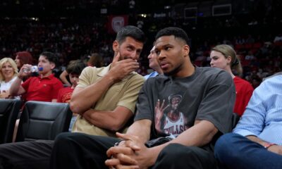 Tennis star Novak Djokovic, left, speaks with Giannis Antetokounmpo of the Milwaukee Bucks while watching a EuroLeague playoffs basketball game between Olympiacos and AS Monaco in Piraeus near Athens, Thursday, April 30, 2026. (AP Photo/Petros Giannakouris)
